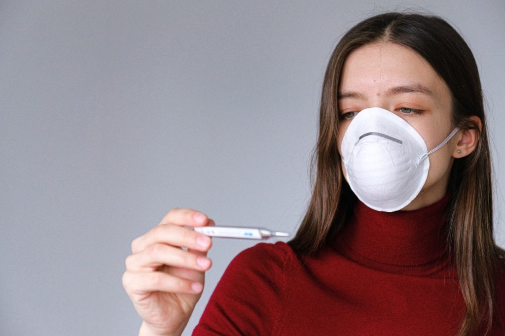 Woman in face mask checking her temperature