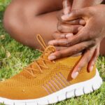 bright yellow colored sneaker, woman holding ankle as if injured