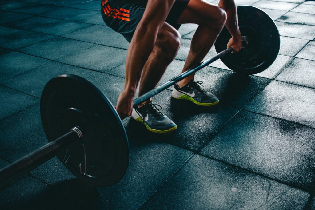 Athletic man lifting a barbell in a dark gym
