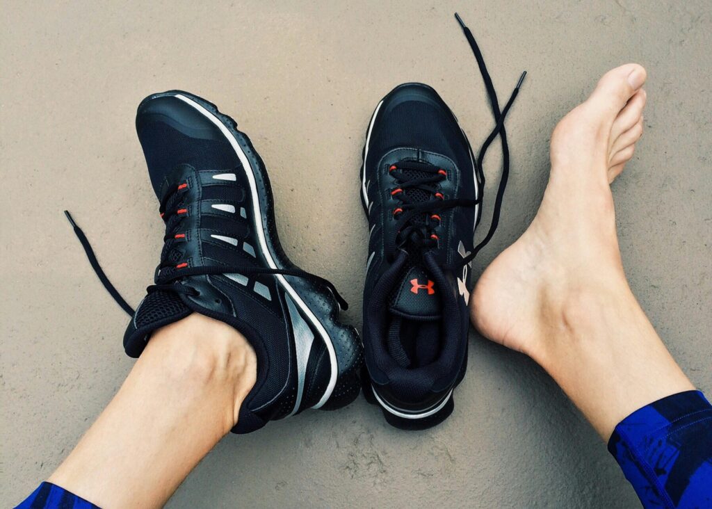 Pair of feet with sneakers on, one shoe off