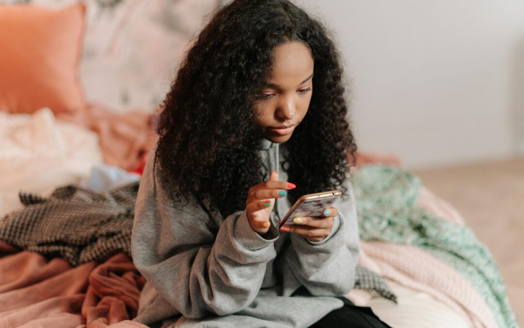girl sitting on bed scrolling her phone looking distressed