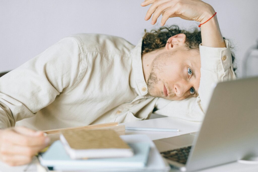 tired man lying in front of a laptop unable to focus