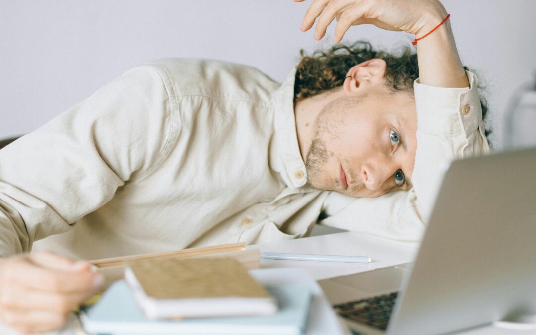 tired man lying in front of a laptop unable to focus