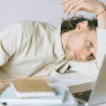 tired man lying in front of a laptop unable to focus