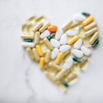 Colorful pills arranged in heart shape on a marble surface, symbolizing health and wellness