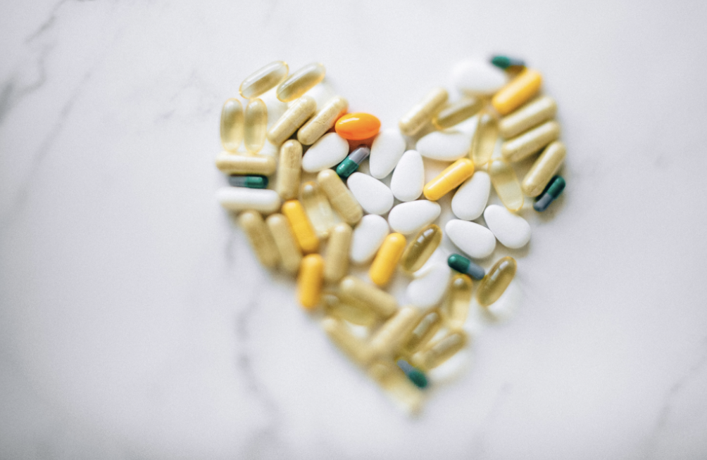 Colorful pills arranged in heart shape on a marble surface, symbolizing health and wellness